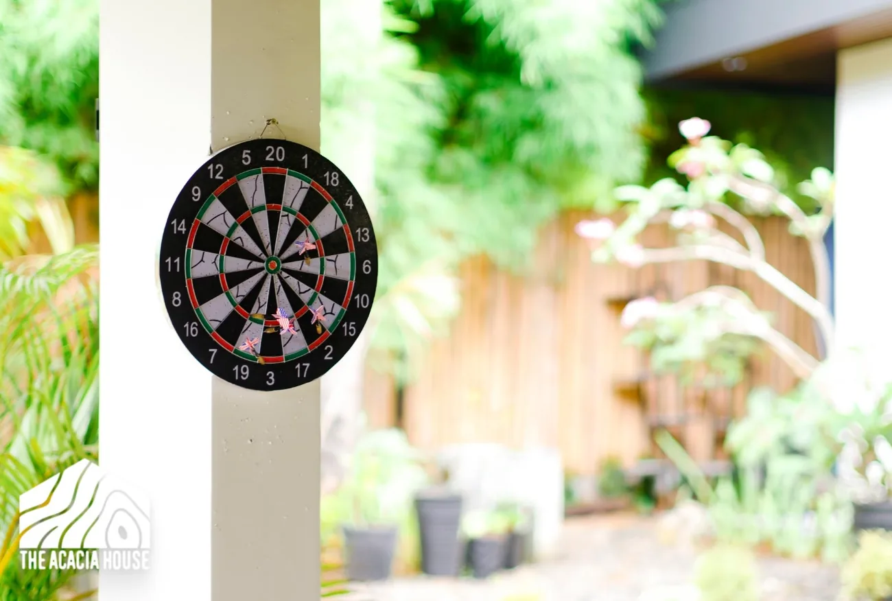 Dartboard hanging on a white pillar beside the garden