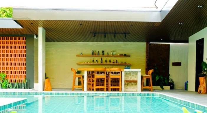 Outdoor bar with wooden stools and shelves of bottles beside the pool